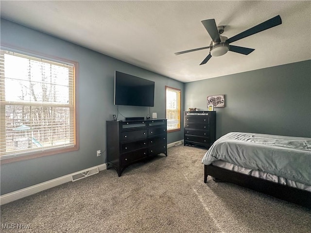 bedroom with ceiling fan, light colored carpet, and multiple windows