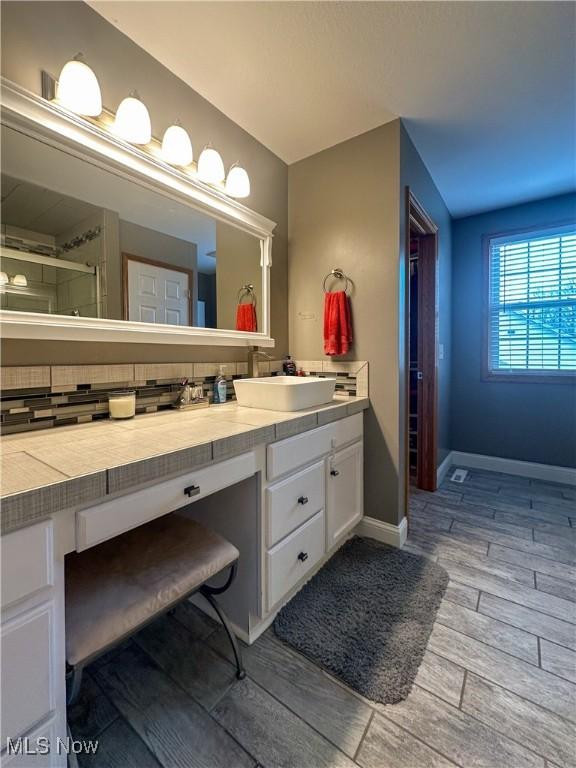 bathroom with wood finish floors, an enclosed shower, vanity, and baseboards