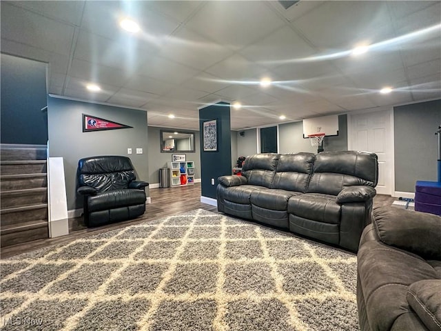 living area featuring a drop ceiling, stairway, baseboards, and wood finished floors