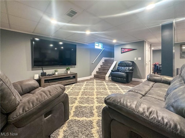 cinema with a paneled ceiling, visible vents, baseboards, and wood finished floors