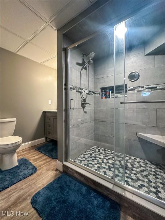 bathroom featuring wood-type flooring, toilet, and a shower with shower door