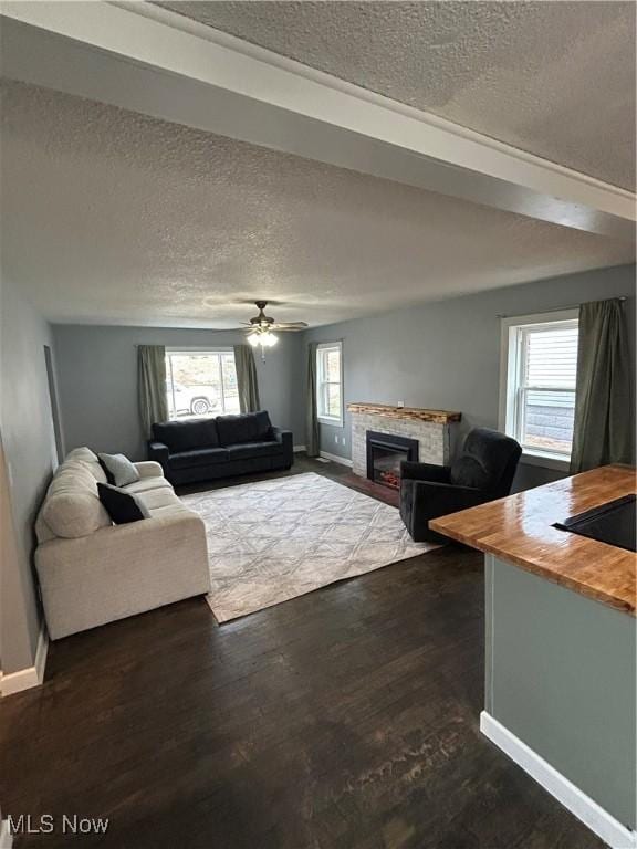 unfurnished living room featuring dark wood-type flooring, a textured ceiling, and ceiling fan