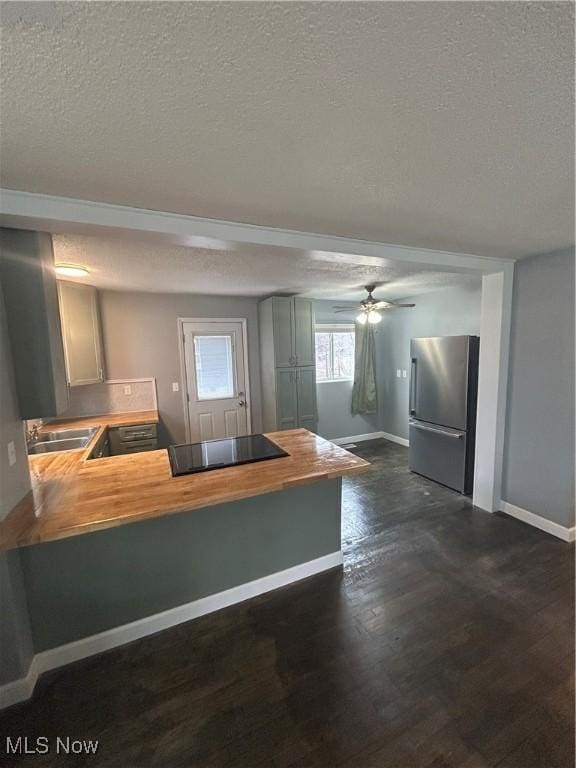 kitchen featuring butcher block counters, high end fridge, black electric cooktop, dark hardwood / wood-style floors, and kitchen peninsula