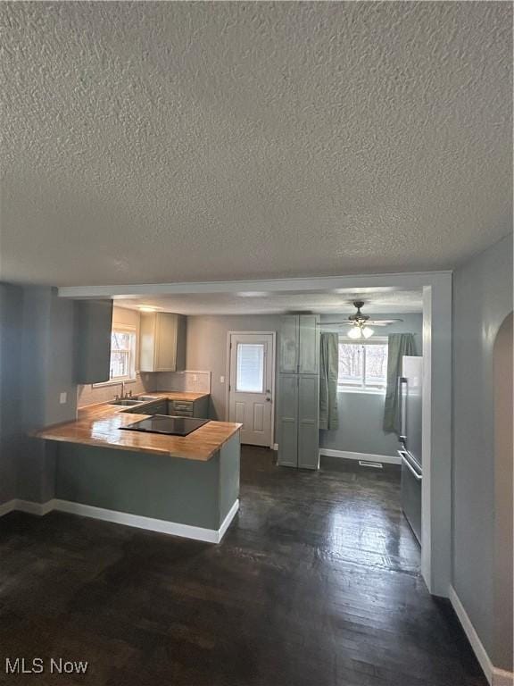 kitchen with dark hardwood / wood-style floors, sink, black electric stovetop, kitchen peninsula, and a textured ceiling