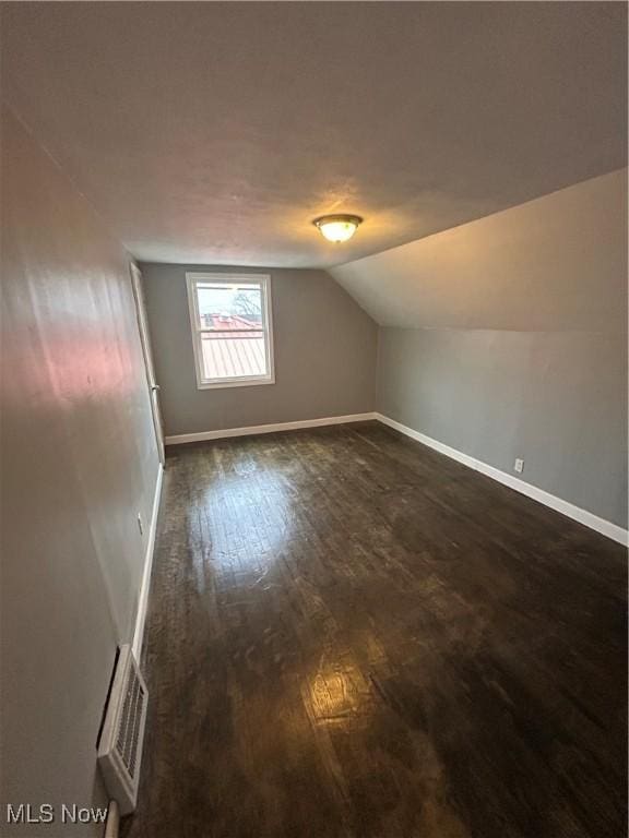 bonus room featuring vaulted ceiling and dark wood-type flooring