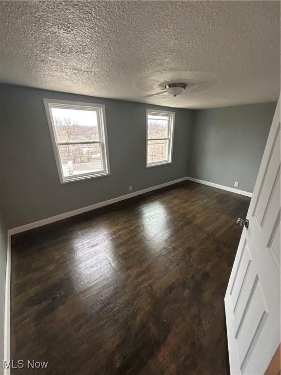 empty room featuring dark hardwood / wood-style flooring and a textured ceiling