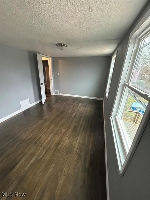 unfurnished room with dark wood-type flooring and a textured ceiling