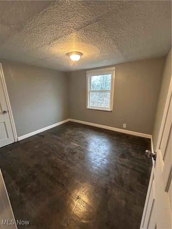 empty room featuring dark hardwood / wood-style floors and a textured ceiling