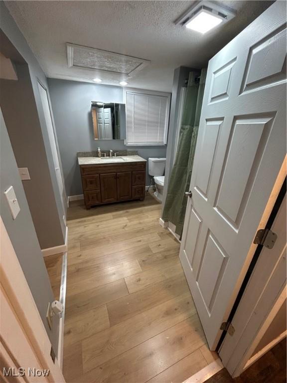 bathroom with hardwood / wood-style floors, vanity, a textured ceiling, a shower with curtain, and toilet