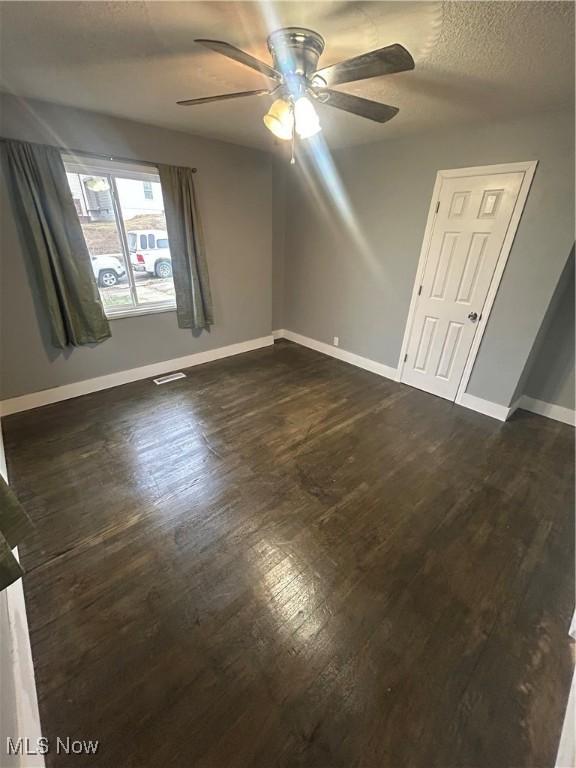 spare room featuring dark hardwood / wood-style floors, a textured ceiling, and ceiling fan