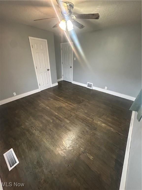 unfurnished room with ceiling fan, dark hardwood / wood-style floors, and a textured ceiling