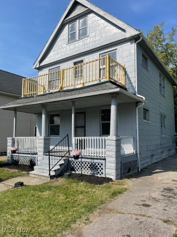 view of front of home featuring a porch, a balcony, and a front yard