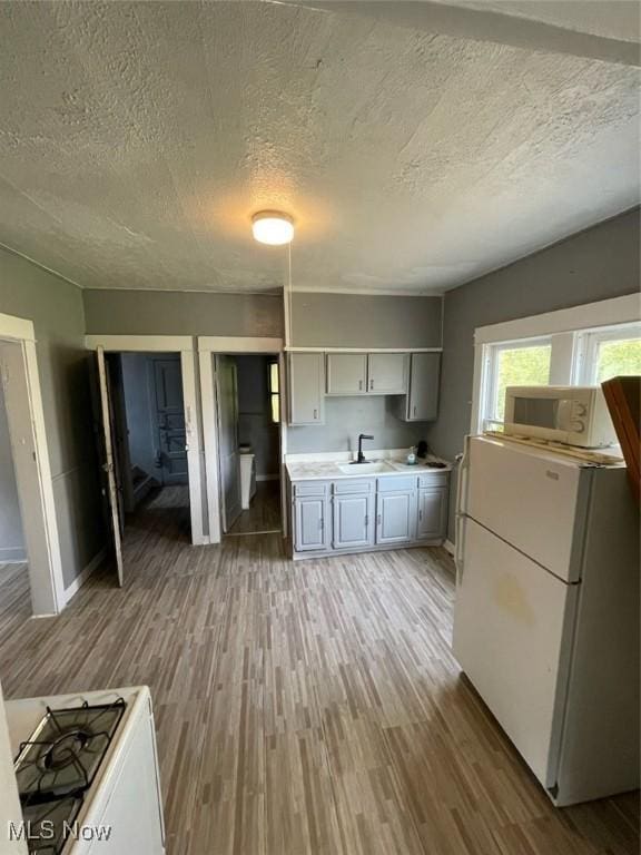 kitchen with sink, white appliances, dark hardwood / wood-style floors, and a textured ceiling