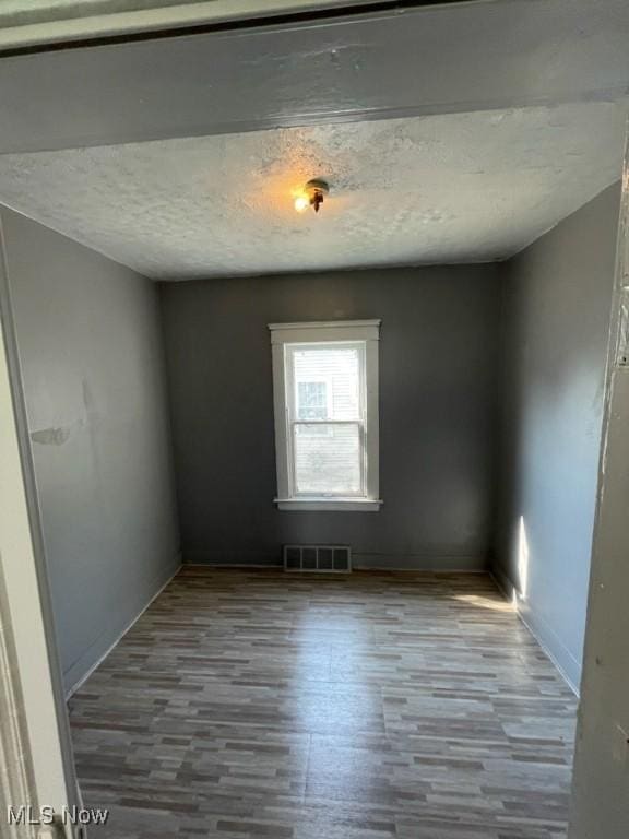 empty room with a textured ceiling and light hardwood / wood-style floors