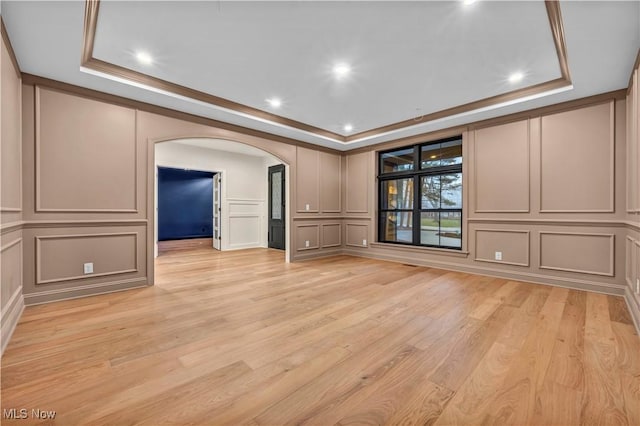 unfurnished living room featuring crown molding, a tray ceiling, and light hardwood / wood-style flooring