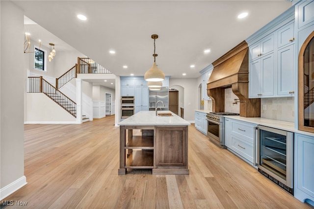 kitchen with stainless steel appliances, light hardwood / wood-style flooring, beverage cooler, and decorative light fixtures