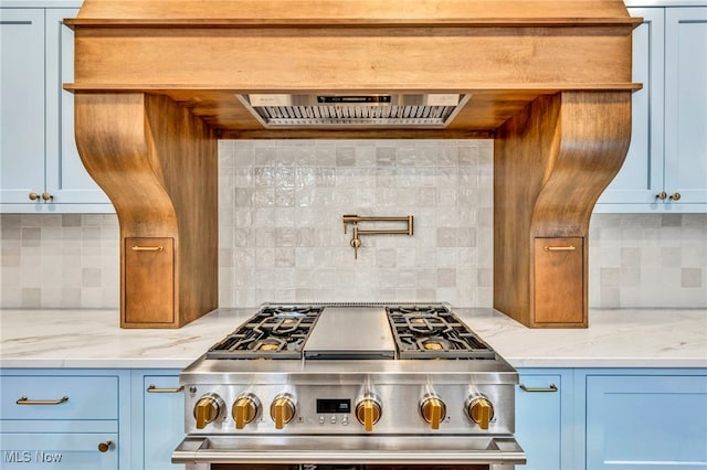 kitchen featuring extractor fan, light stone countertops, stainless steel range with gas stovetop, and backsplash