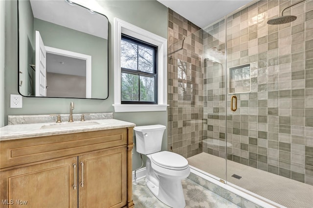 bathroom featuring a shower with door, vanity, and toilet