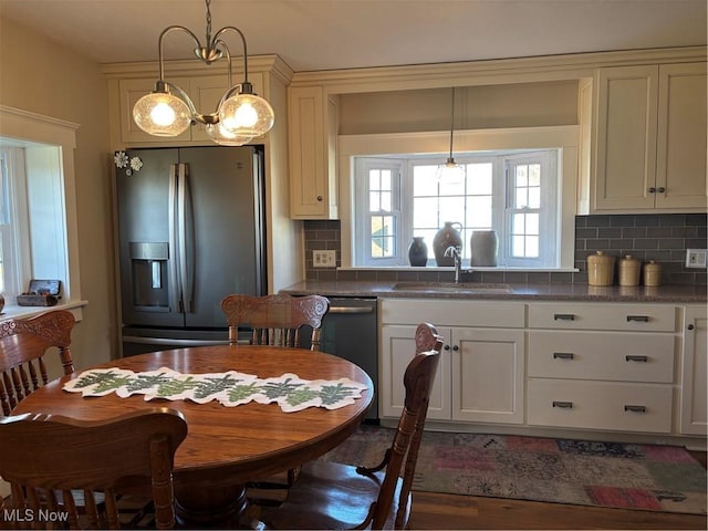 kitchen with pendant lighting, stainless steel appliances, sink, and tasteful backsplash