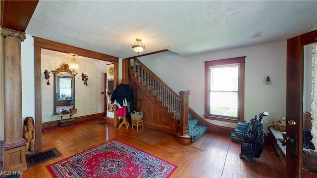 interior space with decorative columns, a chandelier, parquet floors, and a textured ceiling