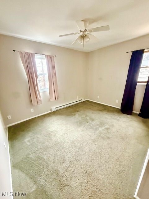 carpeted spare room with a baseboard heating unit, plenty of natural light, and ceiling fan