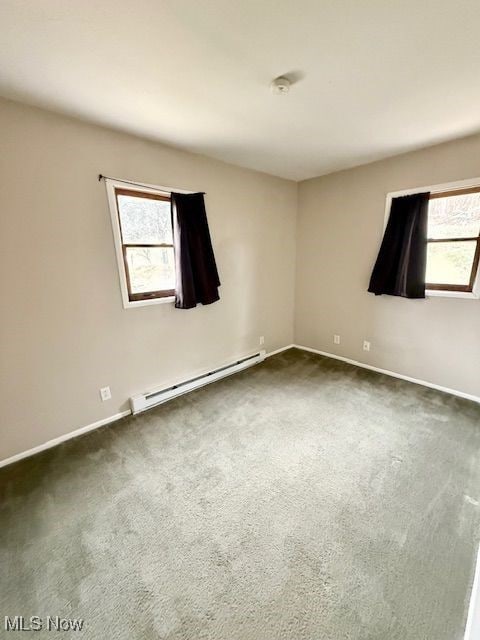 carpeted empty room with a healthy amount of sunlight and a baseboard heating unit