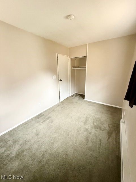 unfurnished bedroom featuring dark carpet and a closet