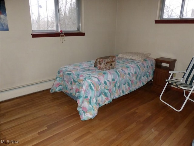 bedroom with baseboard heating and hardwood / wood-style flooring