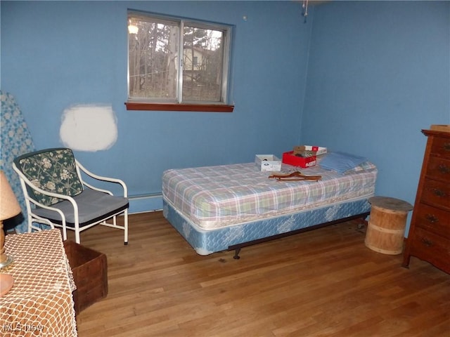 bedroom with wood-type flooring and a baseboard heating unit