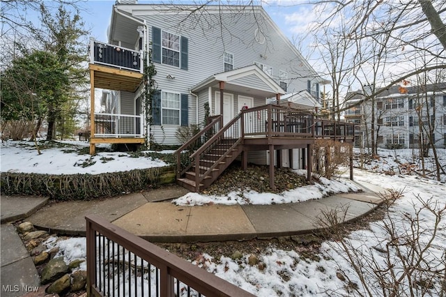 snow covered house with cooling unit and a wooden deck