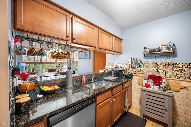 kitchen featuring sink, stainless steel dishwasher, dark stone counters, and a textured ceiling