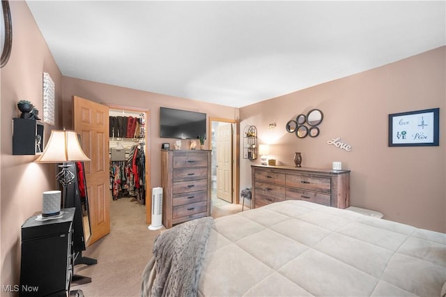 bedroom featuring light colored carpet, a spacious closet, and a closet