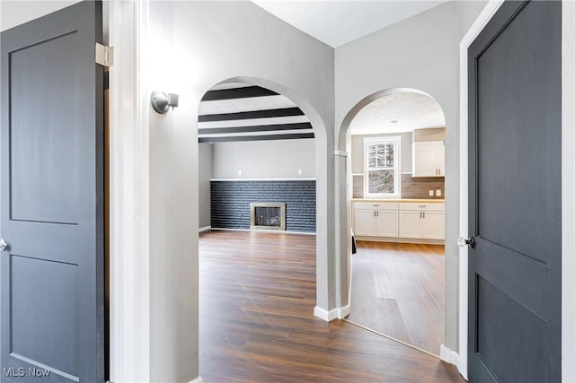 hallway featuring dark wood-type flooring and beam ceiling