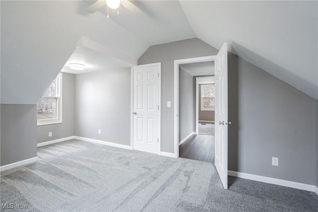 additional living space with lofted ceiling, ceiling fan, and dark colored carpet