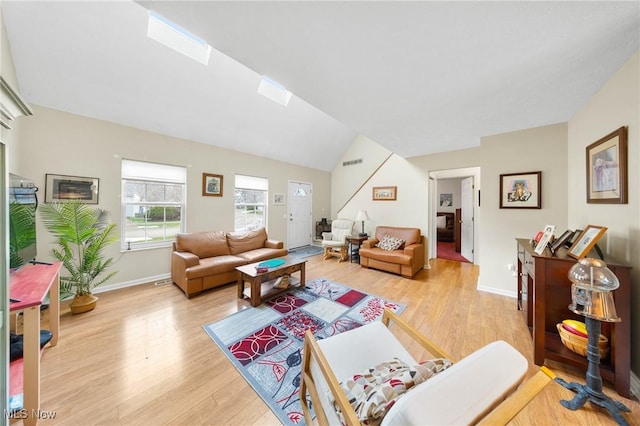 living room featuring lofted ceiling with skylight and light hardwood / wood-style flooring