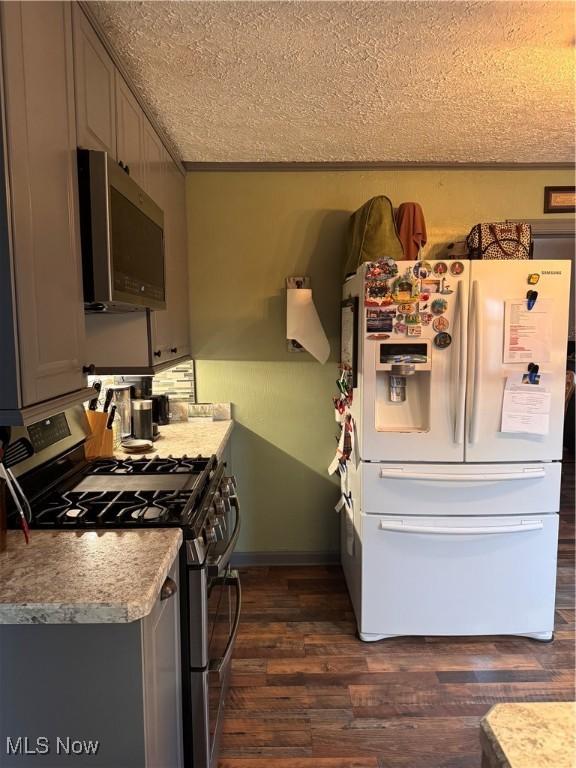 kitchen with stainless steel appliances, gray cabinetry, a textured ceiling, and dark hardwood / wood-style flooring