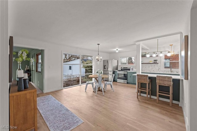 dining space with light hardwood / wood-style floors and a notable chandelier