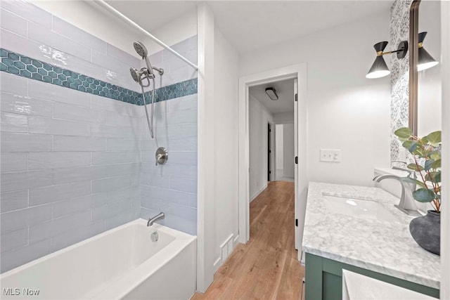 bathroom with tiled shower / bath combo, vanity, and hardwood / wood-style floors