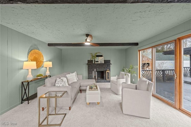 living room with beamed ceiling, a fireplace, carpet, and a textured ceiling