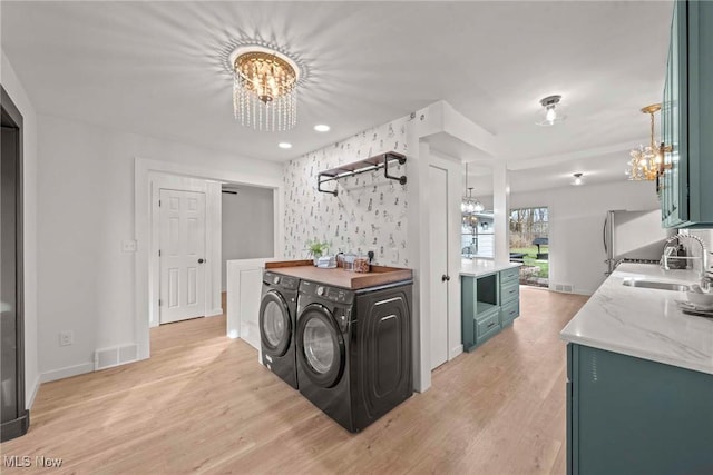 kitchen featuring sink, washing machine and dryer, light hardwood / wood-style floors, and a chandelier