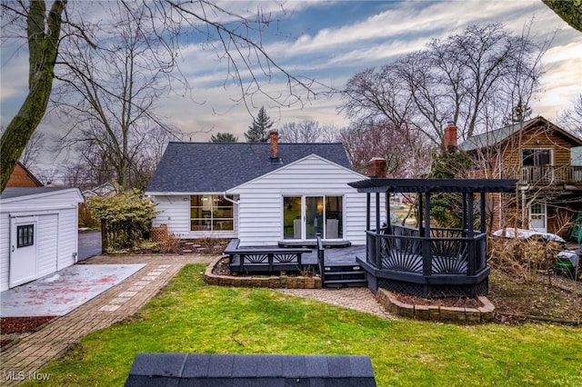 back house at dusk with a yard, a deck, and a storage unit