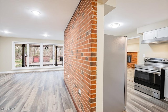 kitchen featuring stainless steel electric range oven, light hardwood / wood-style flooring, and white cabinets