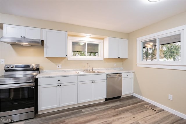 kitchen with stainless steel appliances, sink, wood-type flooring, and white cabinets