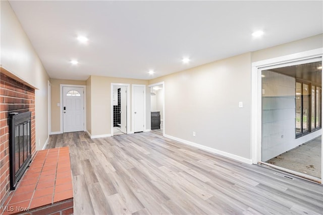 unfurnished living room with a brick fireplace and light wood-type flooring