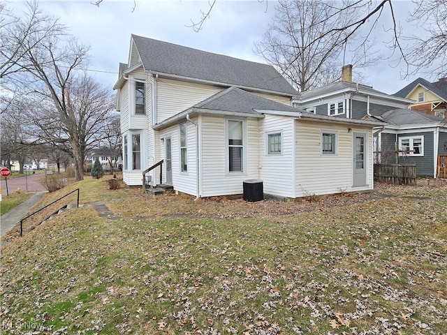 back of property with a yard and central AC