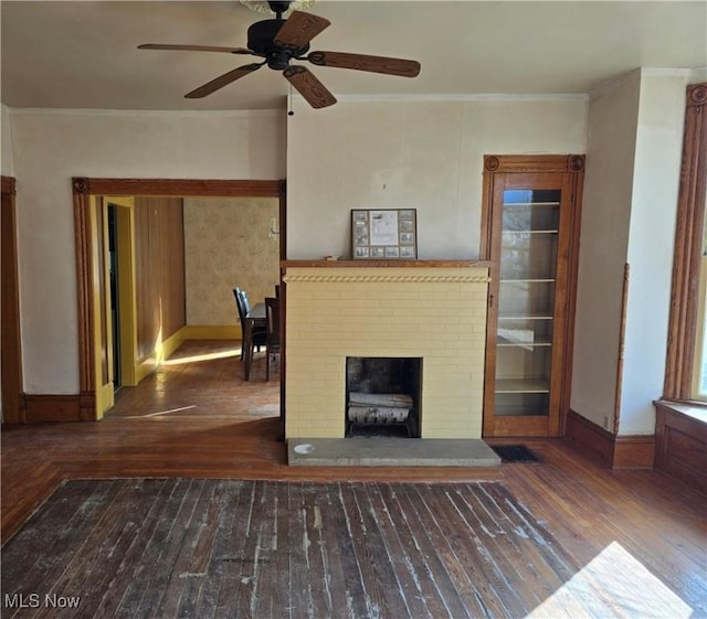 unfurnished living room with ceiling fan, ornamental molding, wood-type flooring, and a brick fireplace