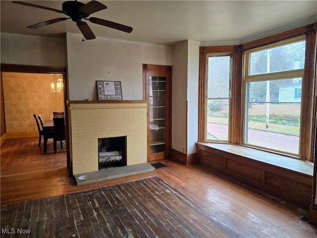 unfurnished living room with ceiling fan, ornamental molding, hardwood / wood-style floors, and a brick fireplace