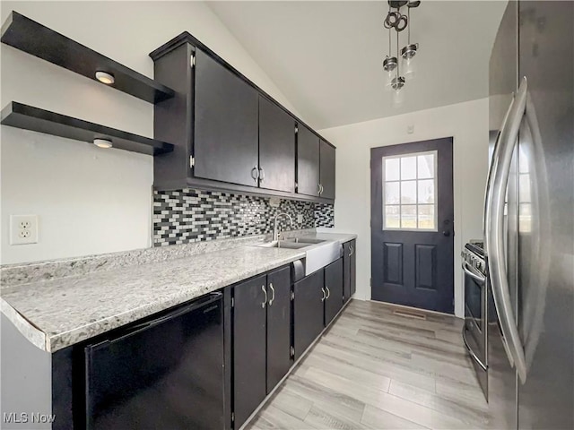 kitchen with pendant lighting, sink, stainless steel appliances, decorative backsplash, and light wood-type flooring