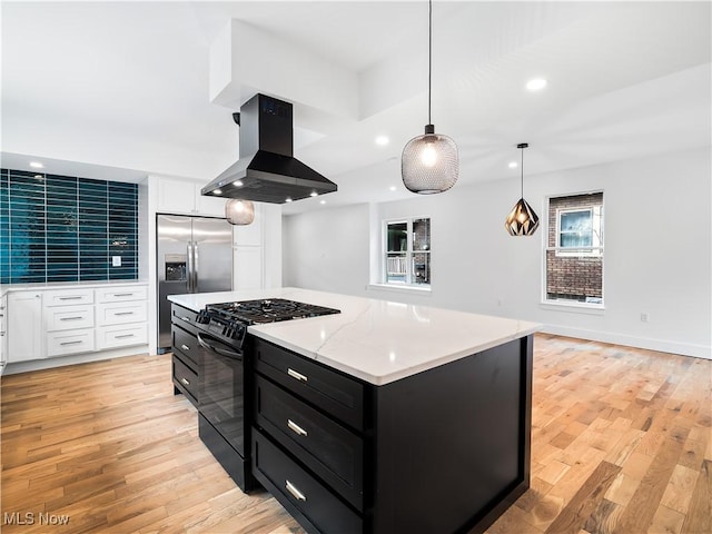 kitchen with pendant lighting, stainless steel fridge, island range hood, gas stove, and white cabinets