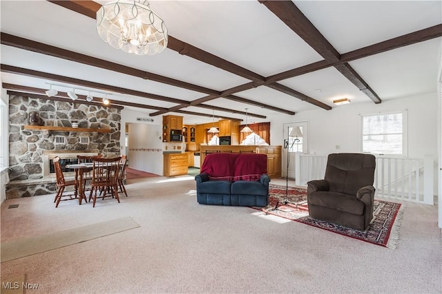 living room with a stone fireplace, light colored carpet, a notable chandelier, and beam ceiling